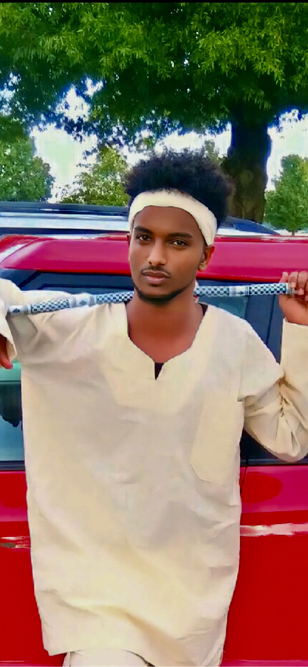 Young Eritrean man in traditional white garment with decorative staff